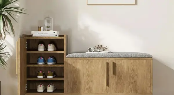 Stylish entryway decor ideas: a wooden shoe cabinet with a padded bench top, open shelves with shoes, and a decorative plant.