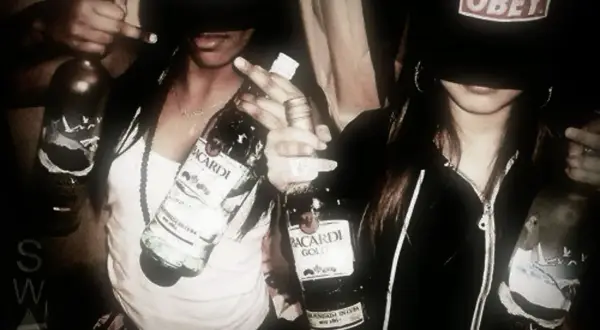 Två personer i fjortis stil med "Obey"-kepsar och Bacardi-flaskor.