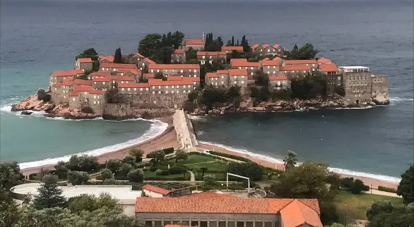 Sveti Stefan, en pittoresk ö med stenhus och röda tak, förbunden med fastlandet via en smal landremsa.