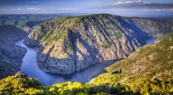 Majestuoso río serpentea entre escarpados acantilados cubiertos de vegetación, creando un paisaje impresionante en los cañones del Sil.