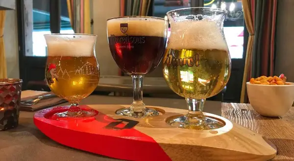 Tre bicchieri di birra su un vassoio di legno, pronti per essere gustati al tavolo.
