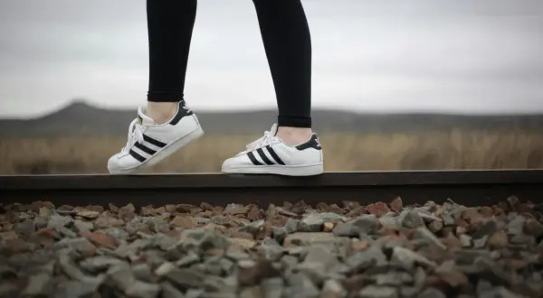 Białe trampki Adidas Superstar z czarnymi paskami i czarne legginsy – idealne buty do legginsów na spacer po torach kolejowych.