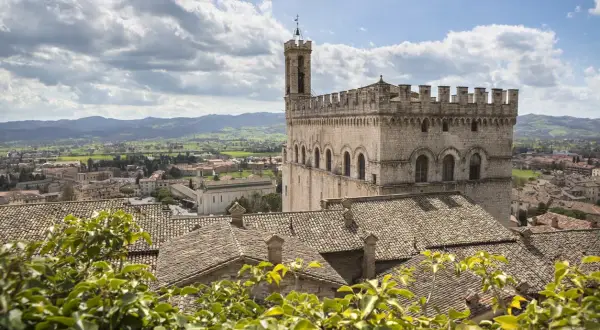 Gubbio da vedere: imponente Palazzo dei Consoli domina il borgo medievale con i suoi tetti in cotto e le colline umbre sullo sfondo.