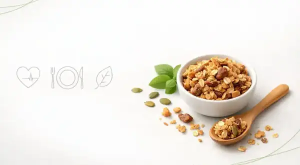 Misternie przygotowana granola w miseczce i na drewnianej łyżce. Czy granola jest zdrowa? Z pewnością tak, gdy zawiera płatki, orzechy i nasiona.