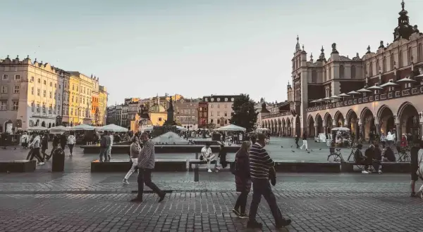 En livlig torgscen i Krakow, perfekt för din reseguide. Människor promenerar förbi historiska byggnader och marknadsstånd.