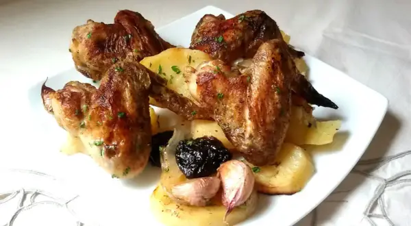 Alitas al horno con patatas, ajo y ciruelas pasas. Un plato casero y delicioso.