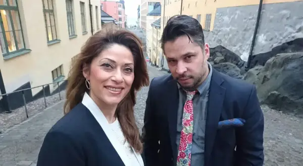 Azita Shariati och en man på en kullerstensgata i Stockholm.