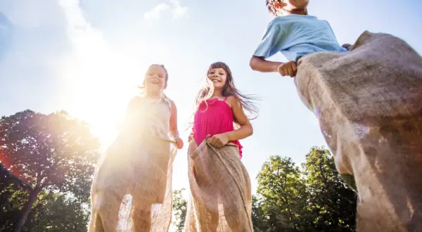 Barn hoppar säcklöpning i solen. Perfekt för tips på femkamp eller en rolig sommardag!