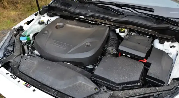 Silnik D2 w Volvo V40, gotowy do pracy. Widać osłonę silnika z logo Volvo, skrzynkę bezpieczników i elementy układu dolotowego.