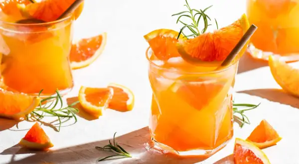 Erfrischender Aperitif mit Prosecco, Orangenstücken und Rosmarin. Perfekt für einen sonnigen Nachmittag.