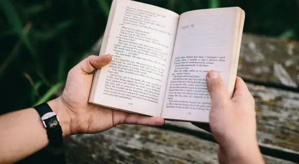 Ręce trzymają otwartą książkę z tekstem. To może być jedna z **książek sensacyjnych top 10**, idealna na relaksujący wieczór.