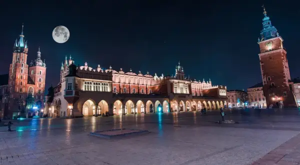 Kraków nocą. Sukiennice i Kościół Mariacki pod księżycem. Wieża Ratuszowa góruje nad Rynkiem.