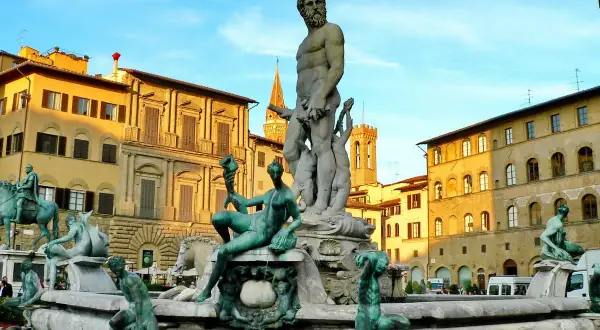 La Fontana del Nettuno a Firenze, con le sue sculture in bronzo e marmo, domina la piazza sotto un cielo azzurro.
