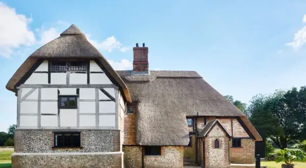 Ein mittelalterliches Bauernhaus mit Strohdach und Fachwerk.