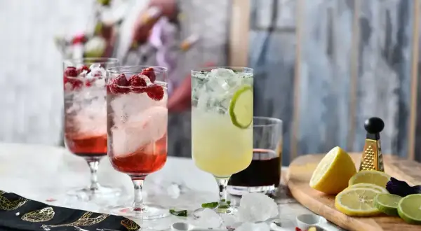 Orzeźwiające drinki z malinami i limonką, a obok składniki do przygotowania domowego alkoholu z wiśni.