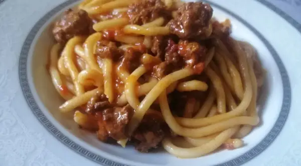 Pici fatti in casa conditi con un ricco ragù di carne, un classico della cucina toscana.