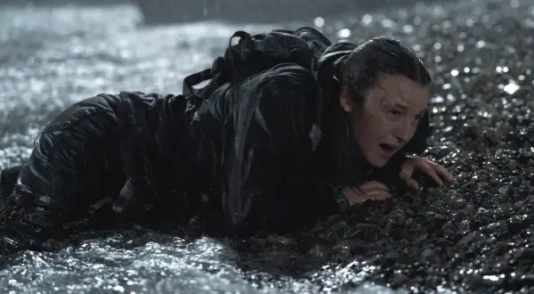 Ellie, wyczerpana i przemoczona, czołga się po kamieniach. To trudne zakończenie The Last of Us 2.