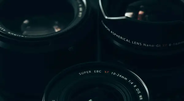 Three Fujifilm lenses, including the XF 10-24mm, are arranged for a street photography shoot.