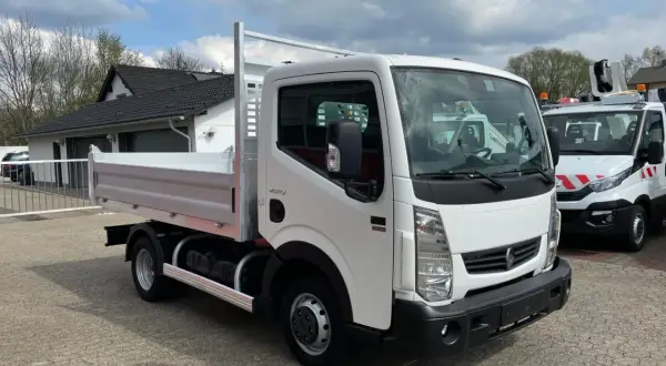 Biały Renault Maxity z otwartą skrzynią ładunkową stoi na placu.