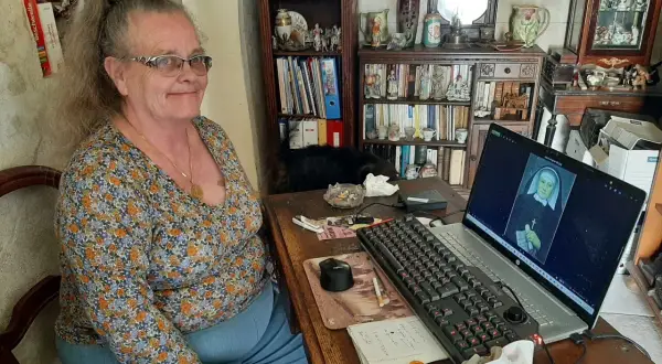 Une femme consulte des archives en Sarthe sur son ordinateur, où s'affiche le portrait d'une religieuse.