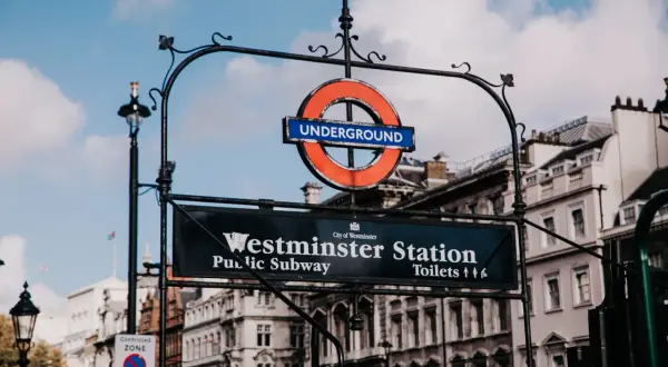Znak Westminster Station, ikona metra londyn ceny. Klasyczny okrągły symbol "Underground" nad tablicą z nazwą stacji i informacją o toaletach.