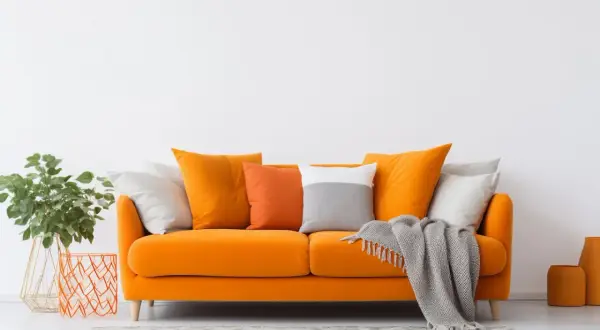 Divano arancione acceso, un'ispirazione per come scegliere il colore del divano. Cuscini colorati e coperta grigia completano l'arredo.
