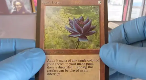 Il Black Lotus, una delle carte più costose di Magic, tenuta con guanti blu.