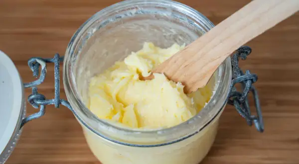 Frisch gemachte Butter in einem Glas, mit einem Holzspatel. So einfach kann man Butter selber machen!