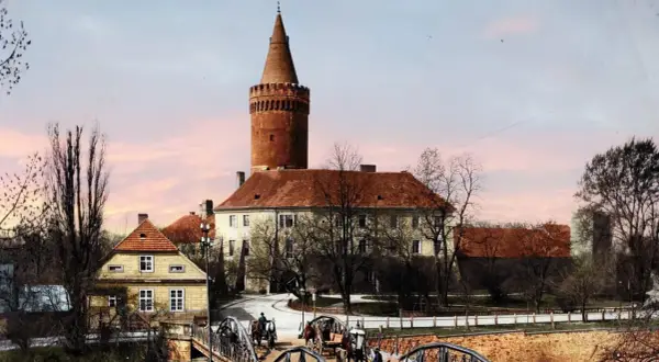 Opole stare miasto: zamek z wieżą, mosty, dorożki i kamienne domy pod różowym niebem.