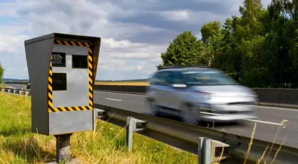 Un appareil de contrôle homologué en mouvement, un radar de vitesse sur le bord de la route, observe une voiture passer à toute allure.