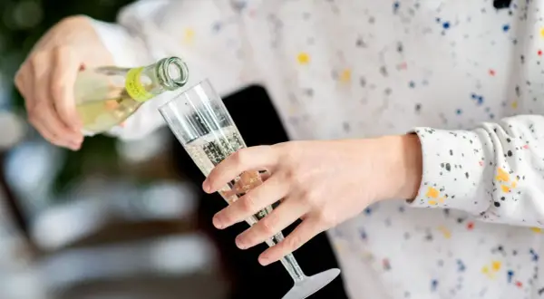 Sekt wird in ein Glas gegossen. Die Frage, wie lange ist Sekt haltbar, beschäftigt viele Genießer.