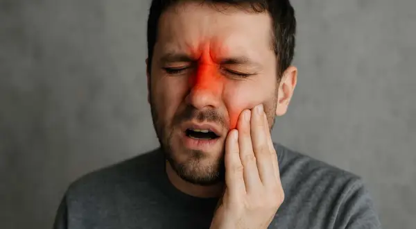 Man med smärta i ansiktet, rödmarkerad panna och kind. Känner igen bihåleinflammation symtom.