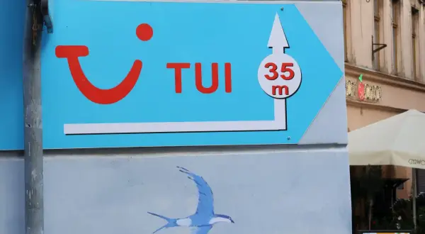 Niebieski szyld TUI z logo i strzałką wskazuje drogę do biura podróży, 35m. Może to być znak, że czas na rezygnację z wycieczki i powrót do domu.