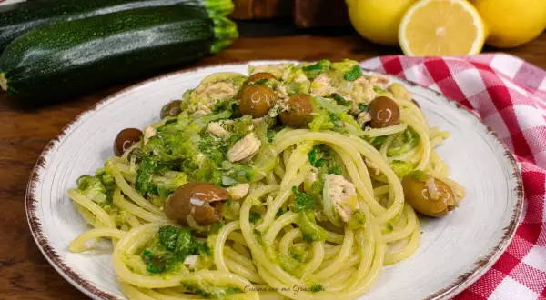 Un piatto invitante di pasta con zucchine e tonno, condita con olive e un tocco di limone.