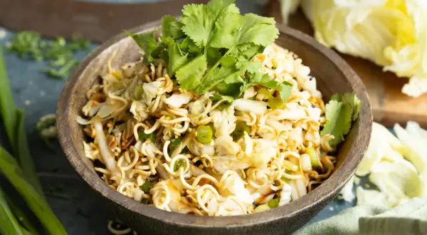 Ein köstlicher mie nudelsalat mit knackigem Kohl, Frühlingszwiebeln und frischem Koriander, garniert mit Sesam.