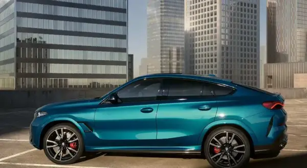 Błękitne x6 BMW lśni na tle nowoczesnych wieżowców.