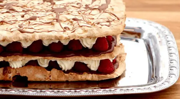 En härlig rice krispies tårta med lager av maräng, grädde, choklad och hallon, dekorerad med chokladsås.