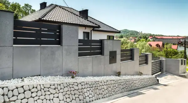 Nowoczesne ogrodzenie z betonu architektonicznego, z czarnymi elementami i kamiennym murkiem. Inspiracja, jak zrobić ogrodzenie z betonu architektonicznego.