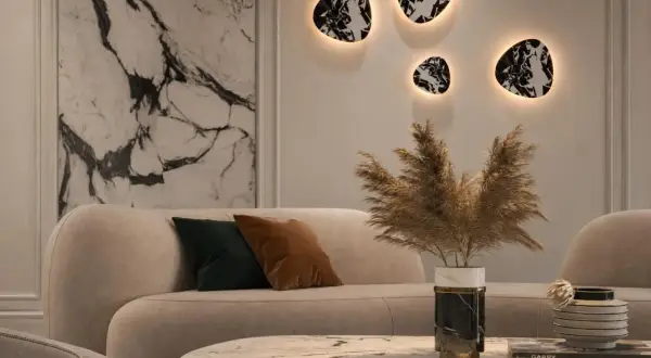 Nowoczesny salon z beżową sofą i marmurowym stolikiem. Na ścianie wiszą dekoracyjne kinkiety z kloszem, tworząc ciepłą atmosferę.
