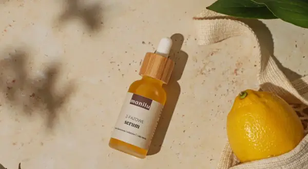 Szukasz idealne serum do twarzy po 50.? Na zdjęciu dwufazowe serum z kwasem hialuronowym, witaminą C i olejem marula, obok cytryny i liści.