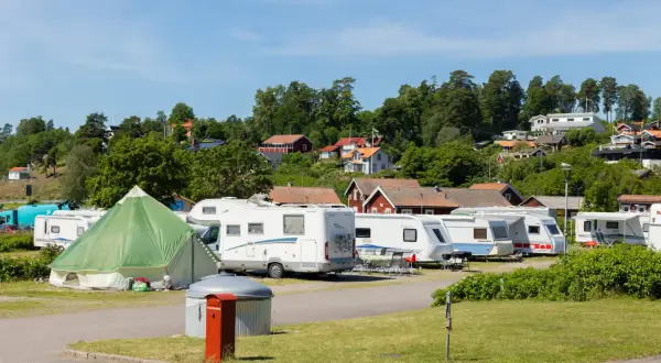 Husvagnar och husbilar står uppradade på en campingplats i Norrköping. En grön kupoltält står i förgrunden.
