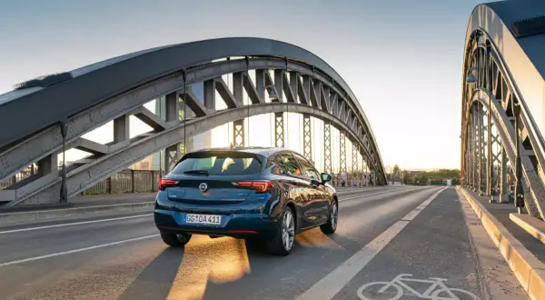 Granatowy Opel Astra jedzie przez most. Zbliża się opel akcja serwisowa, warto sprawdzić stan techniczny auta.