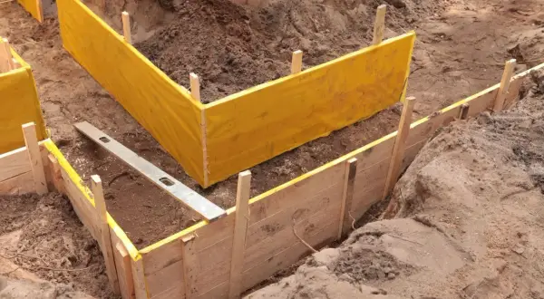 Wykonano wykopy pod fundamenty. Widać drewniane szalunki i żółtą folię.