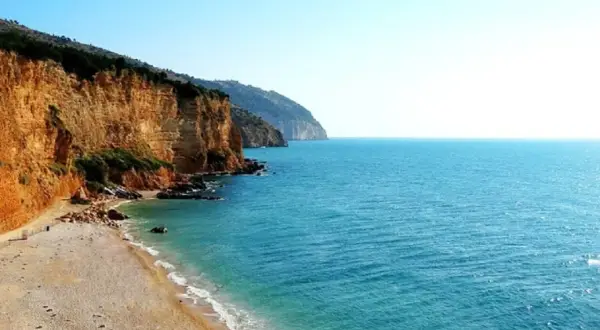 Spiaggia Punta Rossa: scogliere dorate si tuffano nel mare turchese, un angolo di paradiso incontaminato.