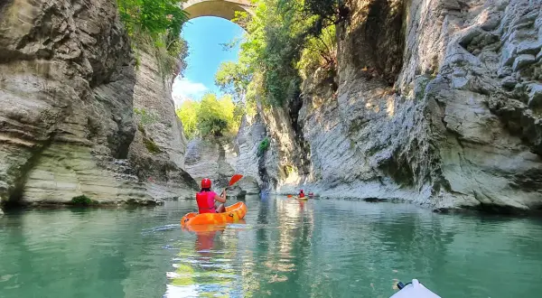 Kayak tra imponenti pareti rocciose, simili a **marmitte dei giganti**, sotto un antico ponte.