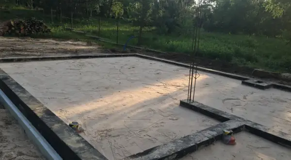 Płyta fundamentowa przygotowana do zimowania. Jak zabezpieczyć płytę fundamentową na zimę? Widać zbrojenie i piasek.