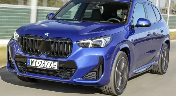 Błękitny BMW X1 2024 z dumą prezentuje swój nowy design, jadąc po drodze.