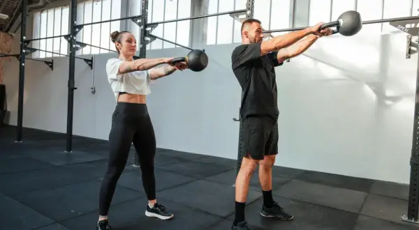 Para, co to jest crossfit, wykonuje ćwiczenie z kettlebell. Intensywny trening buduje siłę i wytrzymałość.
