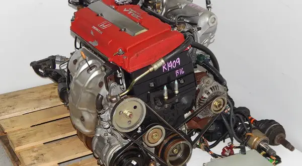 Silnik Honda VTEC z czerwonymi pokrywami zaworów, na drewnianej palecie.