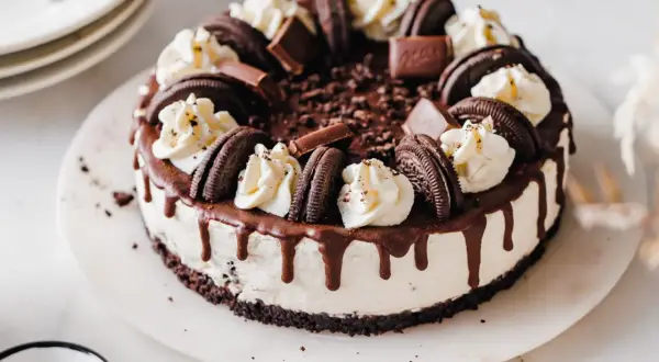 Ein köstlicher Oreo Cheesecake mit Schokoladendrip und Sahnetupfern. Perfekt für jeden Anlass.
